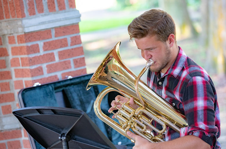 A 鶹ҹ student plays his euphonium outdoors on campus