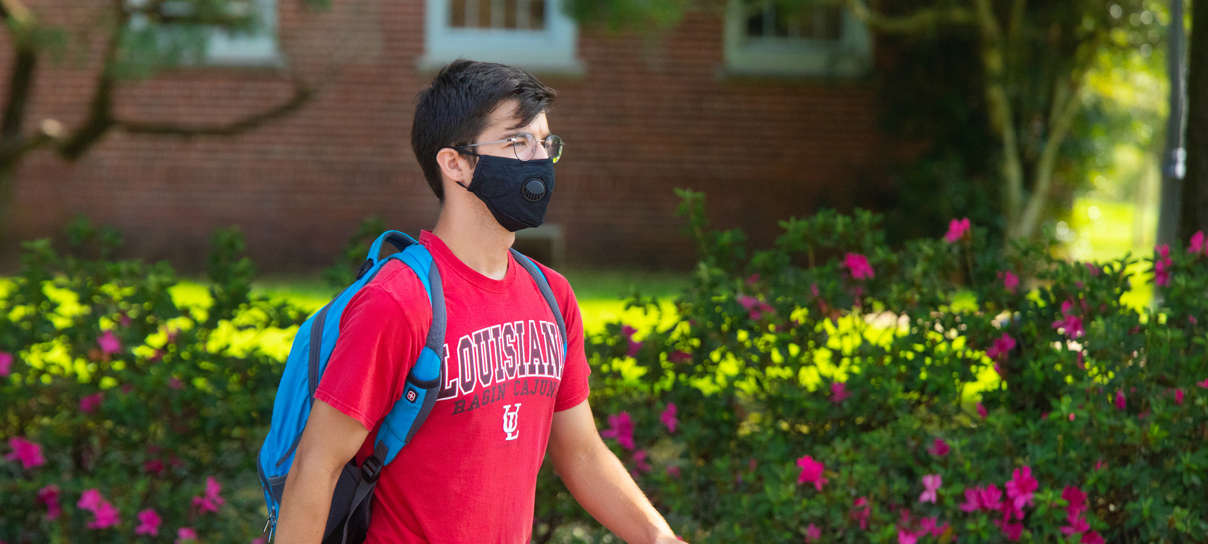 Student walking on 鶹ҹ's campus with a mask