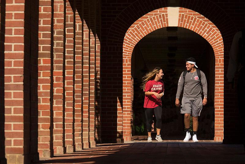 Two 鶹ҹ students walking through the archways on campus
