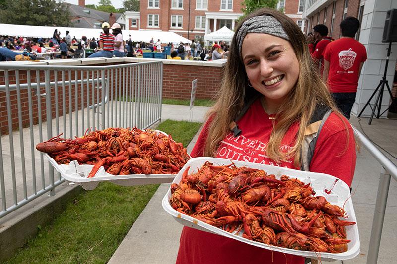 鶹ҹ student holding two trays of boiled crawfish during the annual tradition Lagniappe Day